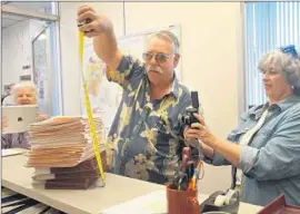  ?? Bradley Zint
Daily Pilot ?? JAY HUMPHREY, a former Costa Mesa councilman and an organizer of the petition drive, measures the stack of paperwork with 6,916 voter signatures.