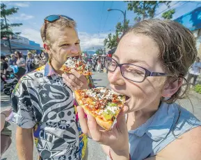  ?? ARLEN REDEKOP ?? Stefan Gronsdahl and Mehan Seiling dig into some pizza while enjoying Italian Day on Commercial Drive.