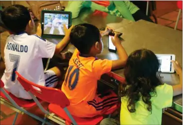  ?? HENG CHIVOAN ?? Children playing with smart phones at home in Phnom Penh recently.