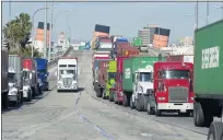  ?? PHOTO BY SAM GANGWER ?? With the smokestack­s of the Queen Mary as a backdrop, trucks line up on Pier J Avenue in 2014 to pick up cargo and containers at the Port of Long Beach, which saw a 43.3% increase in cargo volume in February from the same month last year.