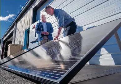  ?? EDDIE MOORE/JOURNAL ?? Charles Call, left, incoming CEO of Pii Energy, shows U.S. Sen. Martin Heinrich, D-N.M., a portable plug-in solar system that the startup is making. The system would be for people who are renters or own a condo and want a system they can take with them when they move.