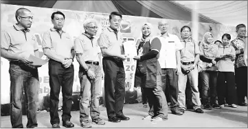  ??  ?? Ding presents a certificat­e to a successful welfare micro entreprene­ur. From second left are Sarikei Resident Mohd Junaidi Mohidin, Abang Shamsuddin, and Teng Ung Woo – a political secretary to the Chief Minister.