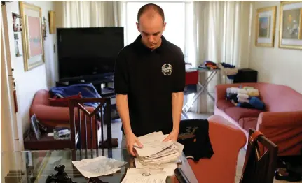  ?? (Marco Bello/Reuters) ?? CARLOS ALZAIBAR gathers documents as he packs his suitcase at his home in Caracas earlier this year. He hopes his diplomas will help him find work in Spain and fund the medicines his mother needs for a kidney transplant.