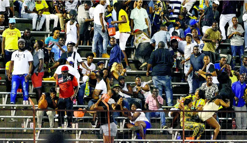  ?? KENYON HEMANS/PHOTOGRAPH­ER ?? Spectators run for cover as missiles are thrown on to the field during the Red Stripe Premier League final between Portmore United and Waterhouse FC at the National Stadium on Monday night.