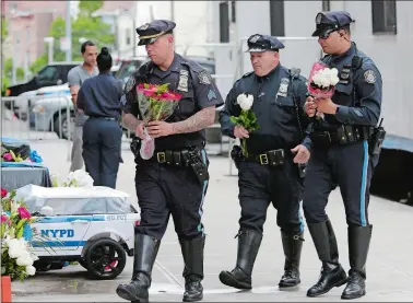  ?? SETH WENIG/AP PHOTO ?? Police officers bring flowers to the 46th Precinct on Thursday in tribute to police officer Miosotis Familia in the Bronx borough of New York. Mayor Bill de Blasio was criticized Friday for attending a protest in Germany about President Donald Trump...