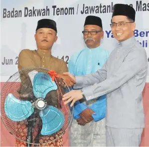  ??  ?? WAKIL dari Surau Kampung Angan-Angan menerima sumbangan dua kipas angin dari Kumpulan Yayasan Sabah yang disampaika­n oleh Andi Francis.
