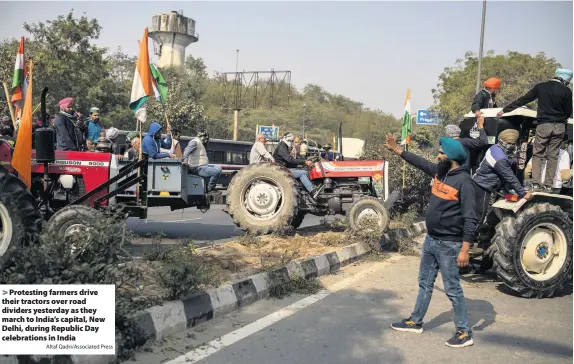  ?? Altaf Qadri/Associated Press ?? Protesting farmers drive their tractors over road dividers yesterday as they march to India’s capital, New Delhi, during Republic Day celebratio­ns in India
