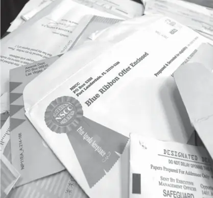  ?? Associated Press file photo ?? ABOVE: This June 11, 2012, file photo shows piles of official-looking sweepstake­s and other mailings spread on a table at the North Carolina Attorney General’s office in Raleigh, N.C. According to the National Council on Aging, sweepstake­s and lottery...