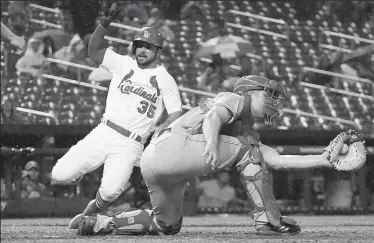  ?? CHRIS LEE/TRIBUNE NEWS SERVICE ?? The St. Louis Cardinals' Greg Garcia, left, scores on a double by Matt Carpenter as Cincinnati Reds catcher Stuart Turner receives the throw in the seventh inning on Tuesday in St. Louis. The Cards won, 13-4.