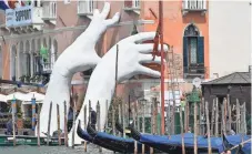  ?? ZSOLT CZEGLEDI, EPA ?? To raise awareness of the impact of global warming, Italian artist Lorenzo Quinn’s sculpture depicts giant hands holding up the side of the Ca’ Sagredo Hotel in Venice, Italy, as part of the 57th Internatio­nal Art Exhibition. The exhibit opened this...