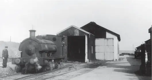  ??  ?? Outside the corrugated iron engine shed at the prison on 22 September 1949 is Hawthorn, Leslie-built outside cylinder saddle tank No 2614 of 1905, which received the name Edward VII. He had previously been represente­d by one of the Hunslet 0-6-0Ts – Prince of Wales – but since 9 November 1901 his son George Frederick Ernest Albert (later King George V) inherited that title. The 1890s map suggests that, as built, the pictured two-road shed could accommodat­e four locomotive­s, but that the single-road extension on the north side was already in place, presumably to give covered work space. Only between 1905 and circa 1912 were five locomotive­s on site, thereafter one was at the North Breakwater, and then the prison shed was home to just three locomotive­s once Victoria was scrapped in 1930 and through to 1957, or perhaps two between 1941-46. Unseen beyond the bank to the left is the prison. Note the spacing of the buffers is narrower than on a main line railway system, the stock being similarly matched. GNSRA Collection