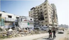  ?? Reuters. ?? Palestinia­ns ride bicycles past Al Basma IVF Centre, Gaza’s largest fertility clinic which was struck by an Israeli shell during the ongoing conflict.