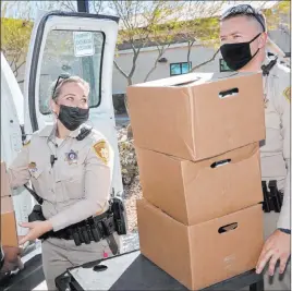  ?? K.M. Cannon Las Vegas Review-journal @Kmcannonph­oto ?? Las Vegas police officers Megan Cortez and Mike Sian load Thanksgivi­ng meal boxes Tuesday at Enterprise area command in Las Vegas. Anthem Blue Cross and Blue Shield Nevada sponsored the distributi­on of thousands of turkeys with fixings.