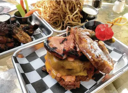  ?? Paul Stephen / Staff ?? The Monte Cristo Burger AKA Doc Holliday features a half-pound beef patty, slabs of griddled ham and cheddar cheese on a bun dipped in waffle batter and fried.