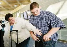  ??  ?? KANSAS CITY: Debbie Alexander checks out her son Jason’s baggy-fitting jeans after he returned from a four-month stay at a weight-loss boarding school at the Kansas City Internatio­nal Airport in Kansas City, Mo. — AP