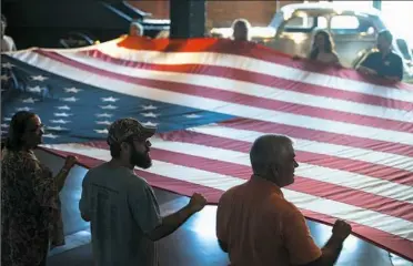  ??  ?? Dan O’Neil, 55, front right, of Houston, participat­es in a flag-folding ceremony in honor of Memorial Day on Monday at the Senator John Heinz History Center in the Strip District.