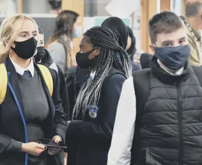  ?? PICTURES: JOHN DEVLIN ?? Pupils at Glasgow’s Holyrood Secondary School appear positive on the first day of new rules requiring youngsters at high school to ‘mask up’ in corridors and when moving between classrooms