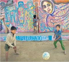  ??  ?? THERAPY FOR THE WOUNDED: The mural behind Rohingya refugee children, who are playing outside their makeshift school in a refugee camp, was created by Artolution.