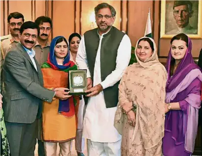  ??  ?? Welcome home: Pakistani Prime Minister Shahid Khaqan Abbasi (centre) presenting a shield to Malala, flanked by her parents, at the Prime Minister’s Office during her visit to Islamabad. — AFP