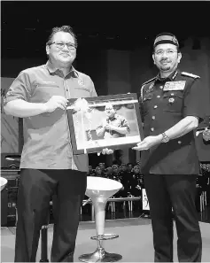  ??  ?? Nur Jazlan (left) receives a souvenir from Mustafar Ali during the opening of Immigratio­n Department’s Sports Convention and Council. — Bernama photo