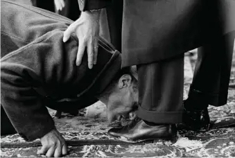  ??  ?? A peasant kissing the feet of Mohammad Reza Shah Pahlavi during a ceremony to distribute land deeds, Isfahan, 1962