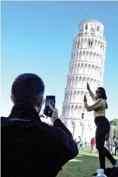  ??  ?? Tourists pose for photos with the Pisa Tower in Pisa.The Leaning Tower of Pisa is now stable and has even straighten­ed slightly thanks to engineerin­g work to save the world-renowned tourist attraction, experts said, — AFP photo