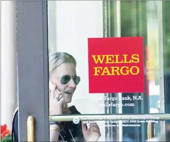  ?? NICHOLAS KAMM/AFP ?? A woman walks into a Wells Fargo bank in Washington, DC, on May 27. Wells Fargo took back another $75 million in pay from two former executives who played key roles in the bank’s fake accounts scandal, the bank announced on Monday.