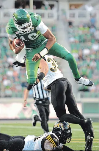  ?? MARK TAYLOR THE CANADIAN PRESS ?? Saskatchew­an Roughrider­s quarterbac­k Brandon Bridge hurdles over Hamilton Tiger-Cats defensive back Mike Daly before fumbling the ball during the first half at Mosaic Stadium in Regina Thursday.