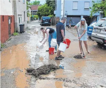  ?? FOTO: HEMMANN/SDMG/DPA ?? Anwohner in Oberstenfe­ld (Landkreis Ludwigsbur­g) kehren nach einem heftigen Gewitter mit Hagel und Starkregen, das in den Abendstund­en über dem Ort niederging, Schlamm und Treibgut von der Straße.