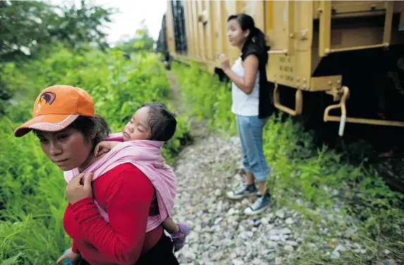  ?? THE ASSOCIATED PRESS PHOTOS ?? Guatemalan migrant Gladys Chinoy, right, waits with more than 500 other migrants, beside the stuck freight train on which they were travelling, outside Reforma de Pineda, Mexico.