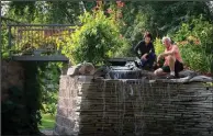  ?? (TNS/Leila Navidi) ?? Yee Lee and her husband, Bryan Johnsen, sit on the retaining wall feature with a 6-foot waterfall, spiral staircase and bridge built by Johnsen.