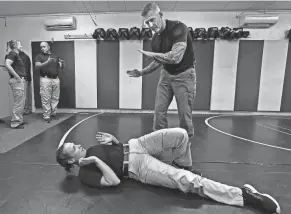  ?? MIKE CARDEW/AKRON BEACON JOURNAL ?? Brian Boss, Akron Police Department training officer, instructs police cadet Morgan Muster as she practices a self-defense movement.