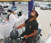  ?? AP ?? A health worker takes a swab sample at drive through facility in Ahmedabad yesterday.