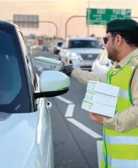  ?? PHOTOS BY NEERAJ MURALI ?? (Left) Lt Col Abdul Rahman Obaid Al Falasi and (right) Captain Khaled Al Hashemi distribute iftar packets to motorists during the Ramadan
Without Accidents campaign by the Dubai Police.