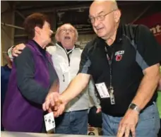  ?? DARREN PITTMAN/THE CANADIAN PRESS ?? Donelda MacAskill, 62, left, is congratula­ted by volunteers after flipping over, and promptly dropping, the ace of spades in Inverness, N.S.