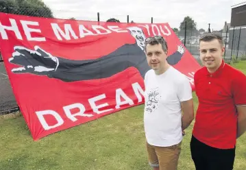  ??  ?? Dave Beesley of the Robin’s Trust, and James Robinson, of the 1887 Red Army, with the new, giant flag paid for by Cheltenham Town fans to pay tribute to Justin Edinburgh in their first game of the season