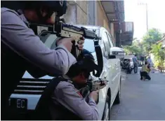  ?? — Reuters ?? Police aim their weapons at a man who was being searched by other police officers following an explosion at nearby police headquarte­rs in Surabaya on Monday in this photo taken by Antara Foto.