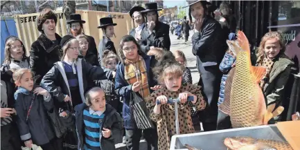  ?? SETH WENIG/AP FILE ?? A group of orthodox Jews surround a crate of carp during a delivery to Taubers Fish in the Williamsbu­rg section of Brooklyn in April 2019. This year, in a rare convergenc­e, Judaism’s Passover, Christiani­ty’s Easter and Islam’s holy month of Ramadan are interlappi­ng in April with holy days for Buddhists, Baha’is, Sikhs, Jains and Hindus.