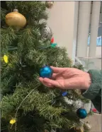  ?? Special to The Daily Courier ?? Barb — a senior who found her footing thanks to the Central Okanagan Food Bank — hangs ornaments on the facility’s Christmas tree.