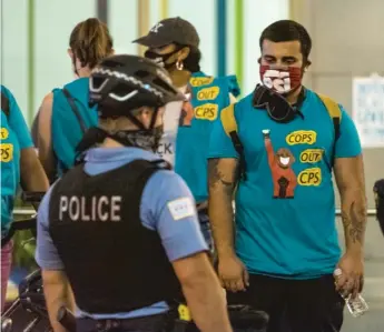  ?? TYLER LARIVIERE/SUN-TIMES ?? Police officers and activists stand outside of Chicago Public Schools headquarte­rs on Madison Street late Monday night.