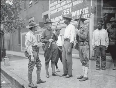  ?? THE ASSOCIATED PRESS FILE ?? In this 1919photo provided by the Chicago History Museum, armed National Guard and African American men stand on a sidewalk during race riots in Chicago. It was 100years ago, in the “Red Summer” of race riots that spread across the United States, but the terror of those days still reverberat­es in a city that continues to grapple with segregatio­n, housing discrimina­tion, and deep tension between residents and police.