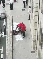  ?? —AFP ?? PARIS: Two emergency members stand by the body of Mickael Harpon, 45-year-old computer expert, shot dead by a policeman after he stabbed four colleagues to death in a frenzied attack at Paris police headquarte­rs.