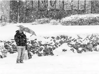  ??  ?? UNA MUJER esperaba el autobús bajo una nevada en Boston, Massachuse­tts, donde se esperaban más de 10 pulgadas de nieve ayer.