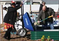  ?? ?? Micah Setnik helps Francean Larsen unload a wheelbarro­w as they help fill a planter in the new learning garden at Faith Food Friday in Vallejo.
