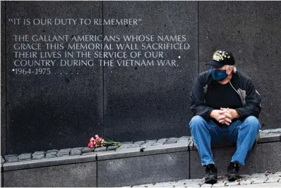  ?? Associated Press ?? ■ Vietnam veteran Kitch Kichula, wearing a protective face mask as a precaution against the coronaviru­s, pays his respects Monday at the Vietnam War Memorial in Philadelph­ia.