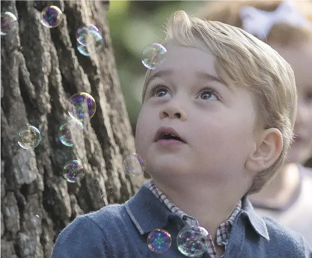  ?? JONATHAN HAYWARD / THE CANADIAN PRESS ?? Prince George reacts to bubbles being blown by his father, Prince William, during a children’s party at Government House in Victoria on Thursday.