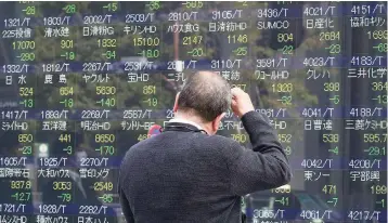  ??  ?? A man checks a share-prices board in Tokyo on Tuesday