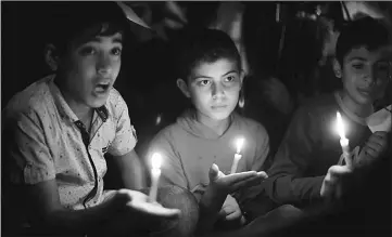  ?? — Reuters photo ?? Palestinia­n boys hold candles during a protest against the blockade on Gaza, in Gaza City on Apr 14.