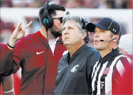  ??  ?? The Associated Press file Washington State football coach Mike Leach, center, watches a replay during a Sept. 3, 2016 game against Eastern Washington in Pullman, Wash. An increase in booth reviews of plays has added considerab­le time to games.
