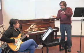  ?? MICHAEL SEARS/MILWAUKEE JOURNAL SENTINEL ?? Instructor Neil Davis (right) gives guitarist Iris Ramirez some pointers during an MYSO Template jazz rehearsal at the Milwaukee Youth Arts Center.